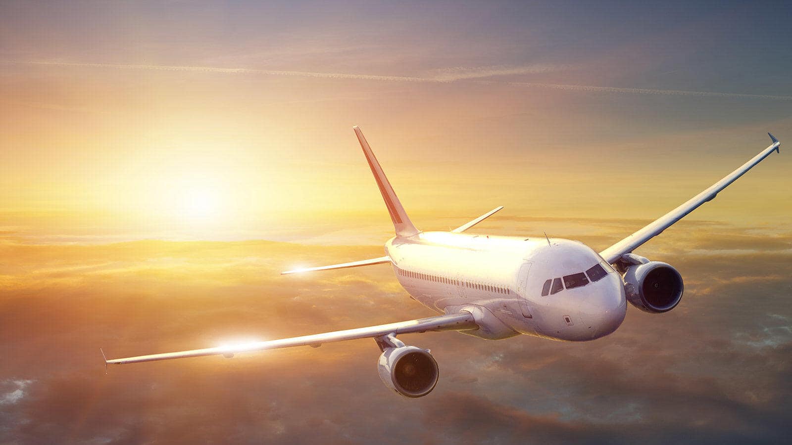 Airplane flying at sunset with clouds below